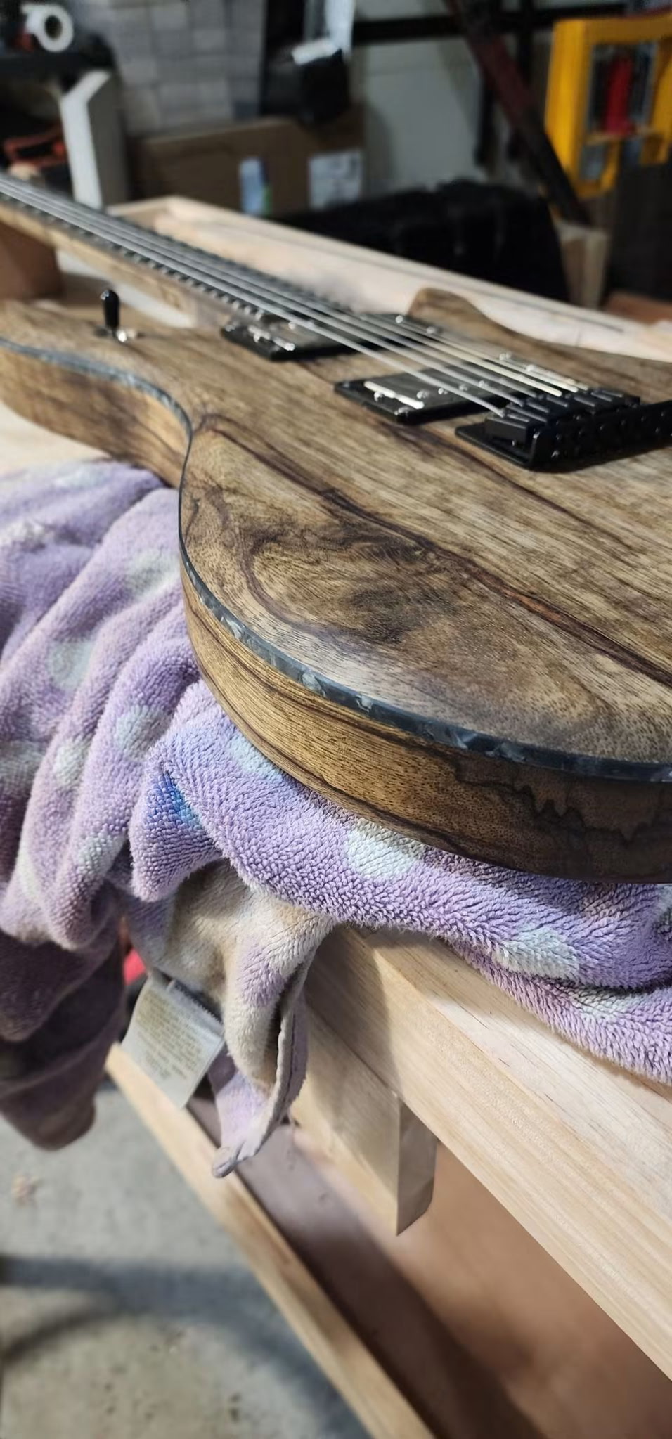 Low angle view of a natural guitar body edge resting on a purple towel